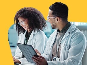 Photograph of 2 scientists wearing a white lab coat are talking
