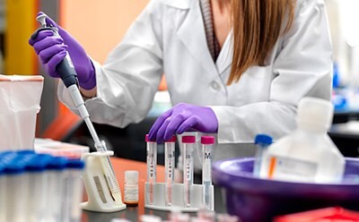 Women in lab coat with peptide, safety gloves, and safety goggles, working in a lab. Women in lab coat with peptide, safety gloves, and safety goggles, working in a lab.