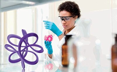 API and Formulation Scientist inspecting a beaker in a laboratory setting