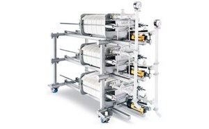 Filtration equipment with multiple cylindrical filters connected by metal piping, set against a white background.