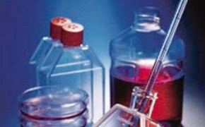 A laboratory setting with various Corning<sup>®</sup> branded glass and plastic labware. Key elements include a large glass bottle partially filled with a red liquid, sealed with a red stopper. There’s also an apparatus that includes a pipette or dropper being inserted into another container. The background is blue.