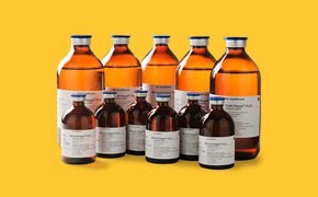 A collection of amber glass bottles of various sizes, labeled with white and blue text, against a yellow background.