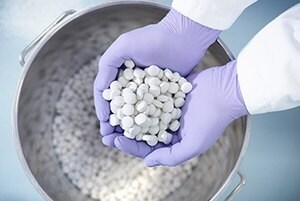 Newly produced tablets held in the gloved hands of a pharmaceutical worker