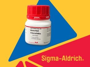 A white container labeled "Assorted Chocolates" with a red lid, positioned against a bright yellow background with blue and red triangular shapes. The Sigma-Aldrich logo is prominently displayed