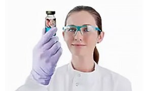 Kobieta-naukowiec w okularach ochronnych trzyma sterylny produkt leczniczy.
