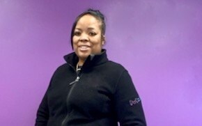 Chevon Adams Chevon Adams가 검은색 플리스를 입고 자주색 벽 앞에 서 있습니다.