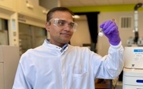 Karwa가 실험실에서 mRNA 순도 측정을 도와주는 분석 기기 옆에 서 있습니다.