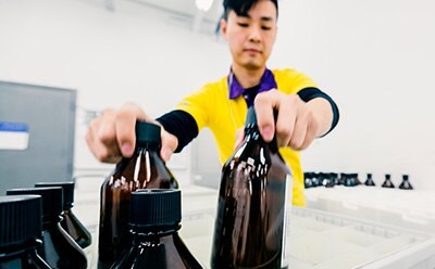 Global manufacturing capabilities to deliver a comprehensive portfolio Worker packing glass bottles into a box