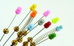 An acupuncture type needle with a blue handle and a gold-colored spiral detail is presented against a white backdrop.